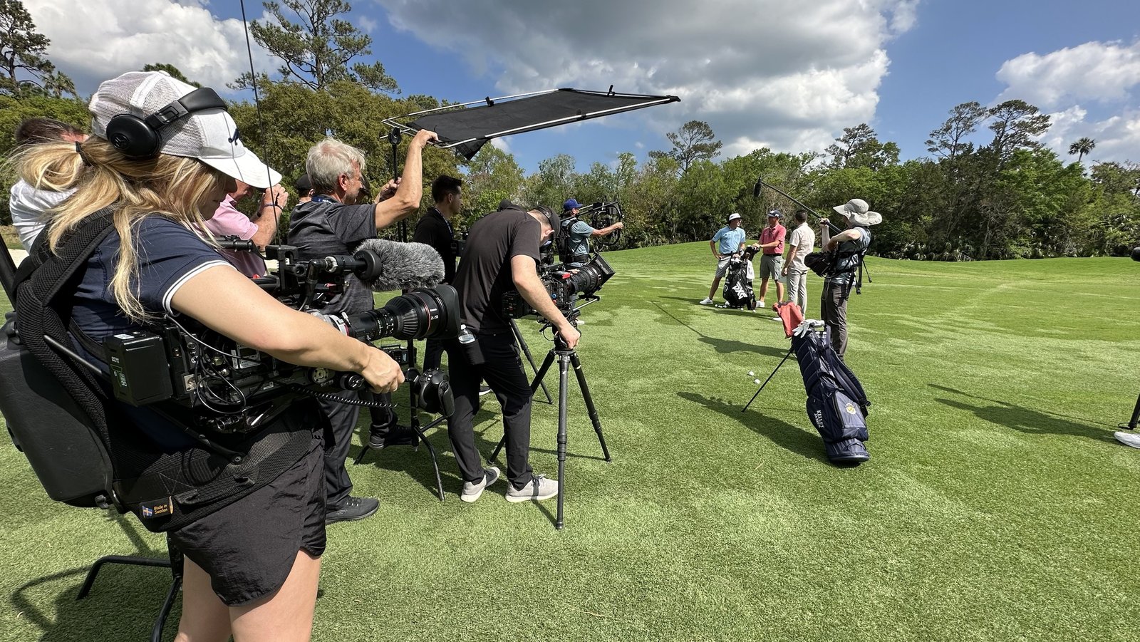 A film crew filming golfers on a course during production of Netflix's Full Swing.
