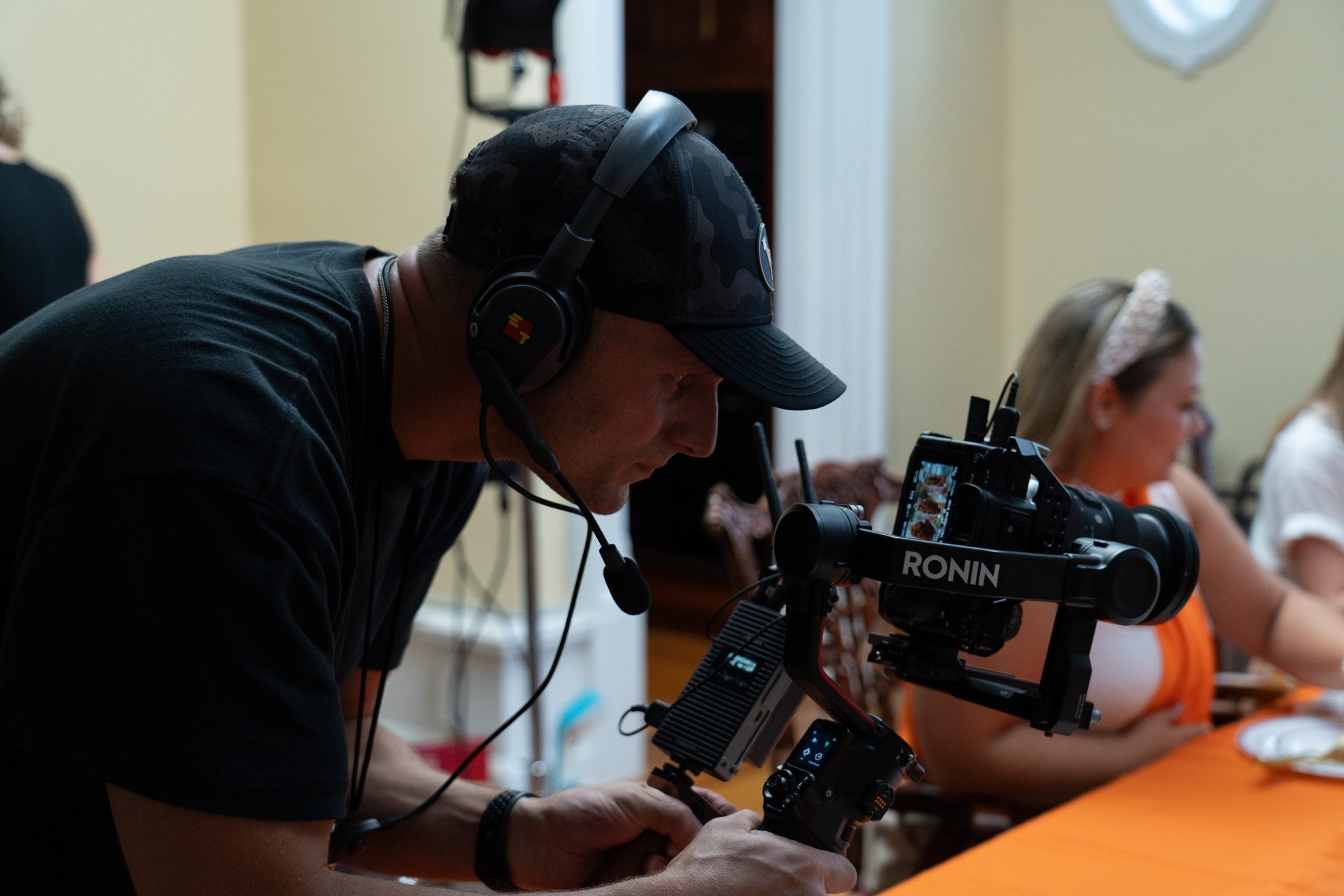 A camera operator works with a gimbal beside the dining-table set on an Applebee’s production.