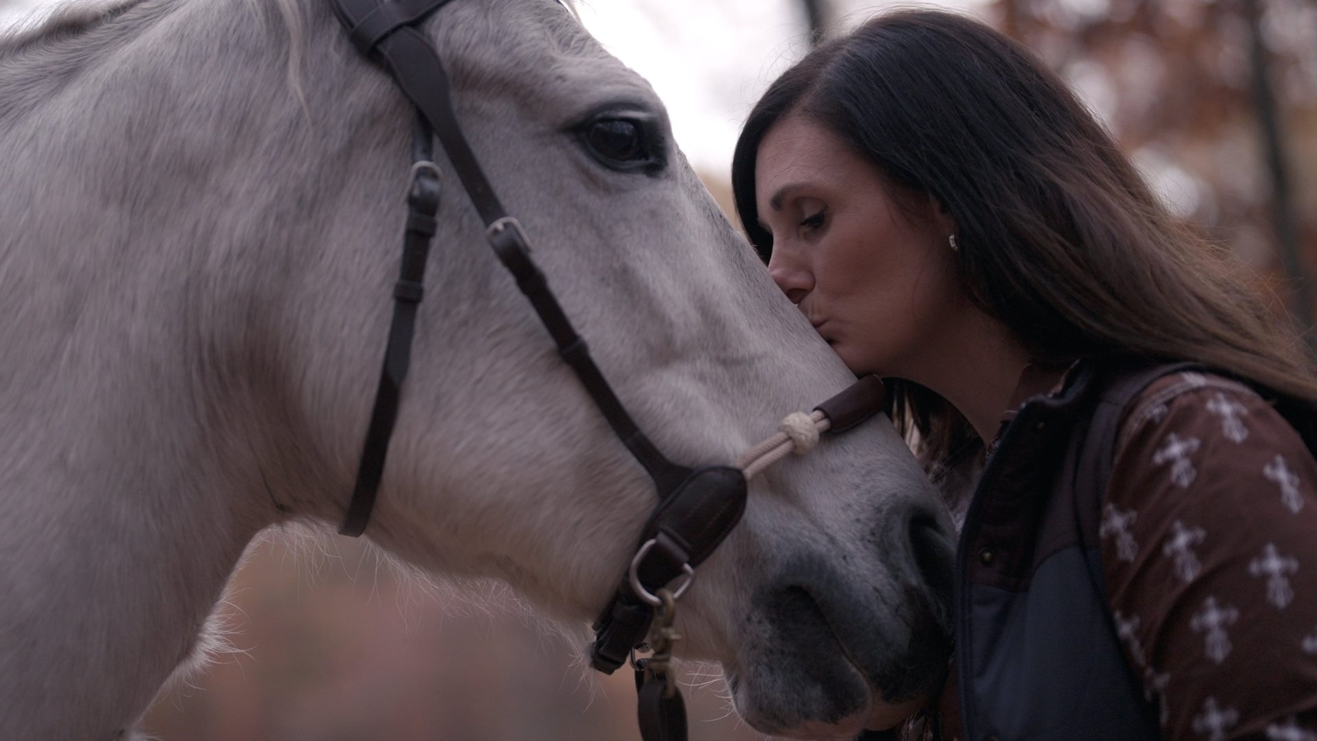 A woman leans close to a white horse in H.O.O.V.E.S.